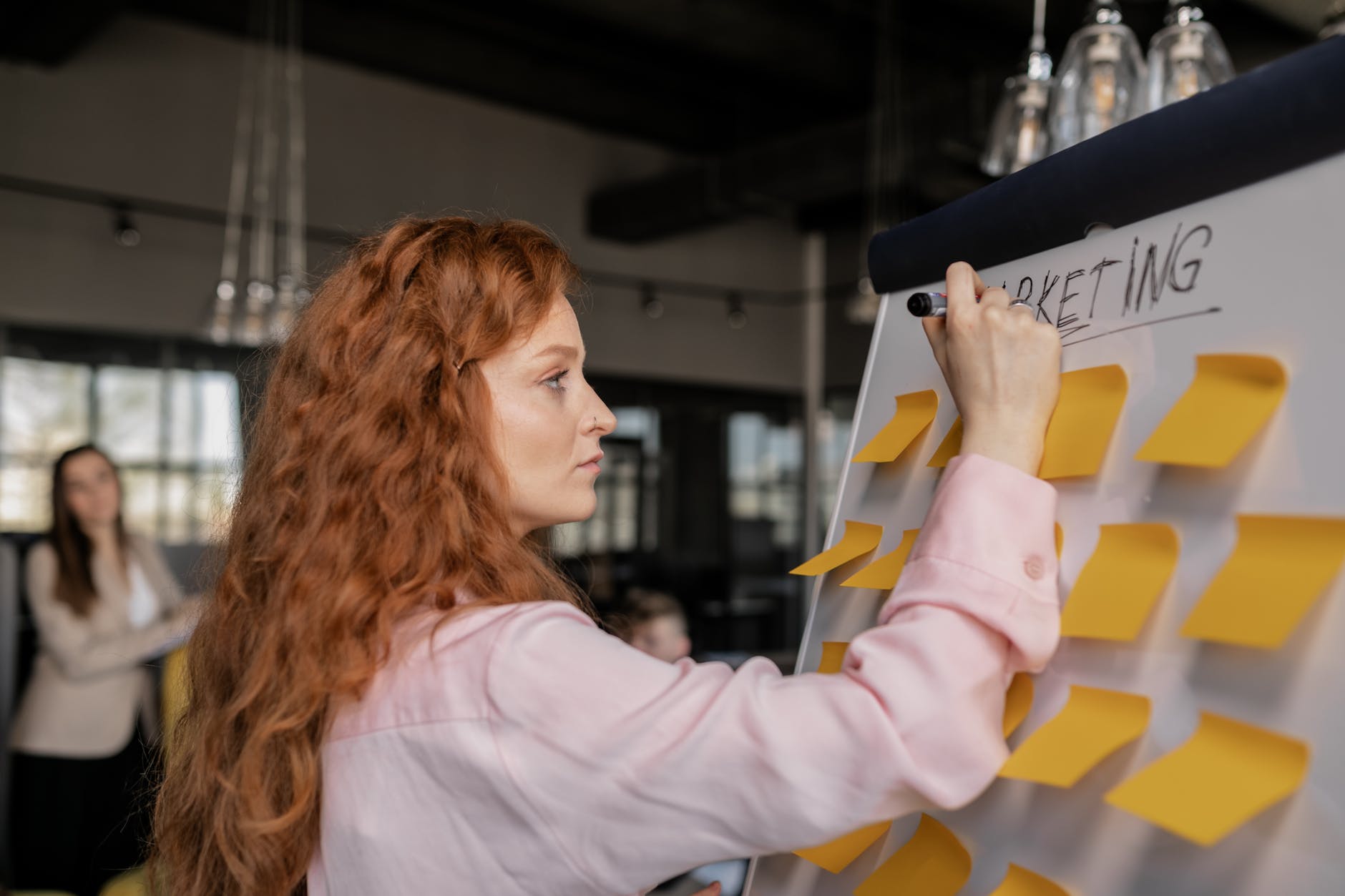 photo of a woman writing on a whiteboard with sticky notes